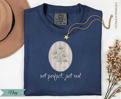 Navy t-shirt with daisy graphic and "not perfect, just real" text.