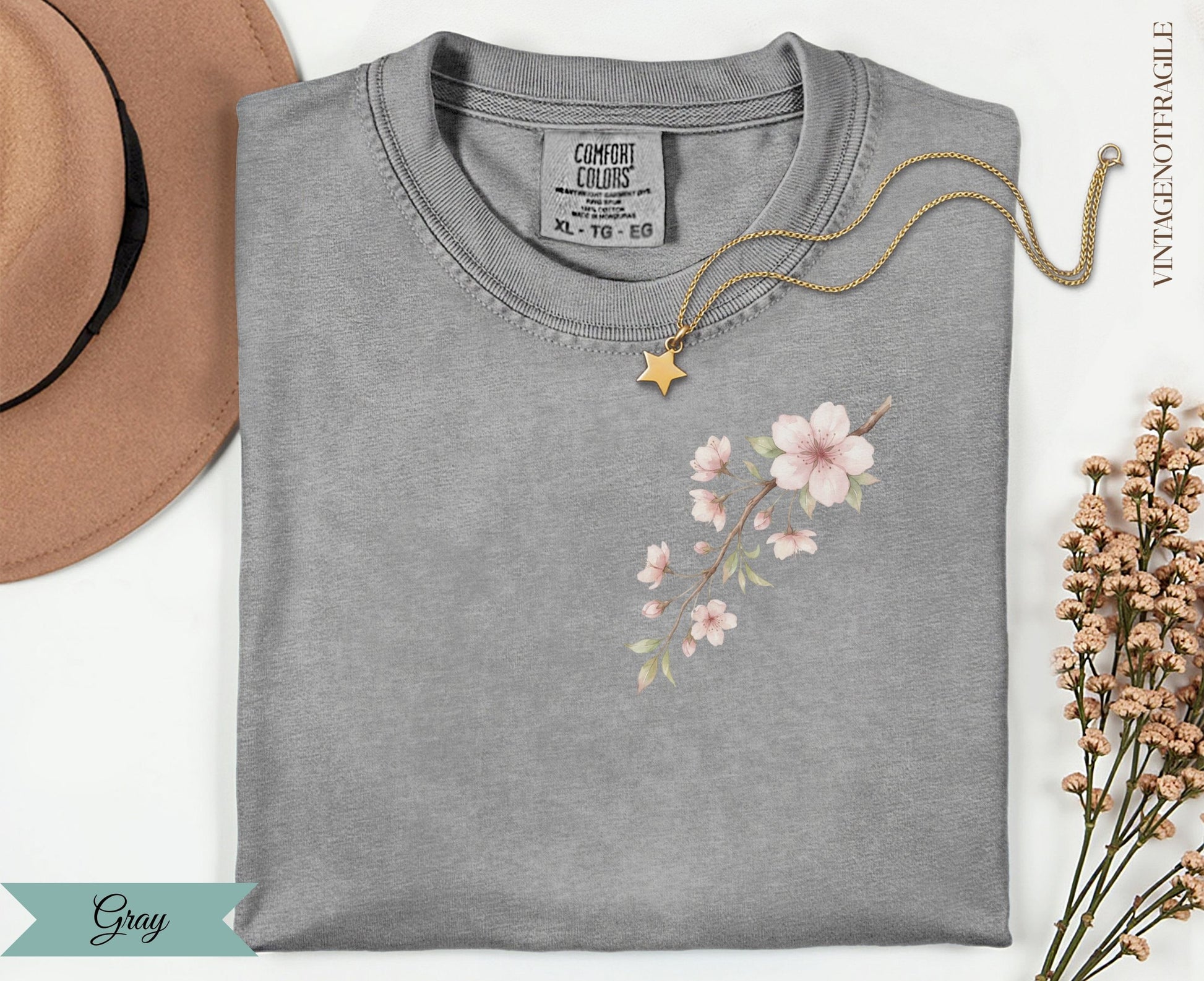 Gray t-shirt with a delicate pink floral branch design and gold star necklace.