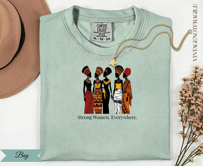 T-shirt with illustration of five women in traditional African attire and "Strong Women. Everywhere." text.