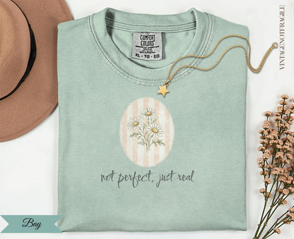 Light green t-shirt with "not perfect, just real" and daisy graphic.