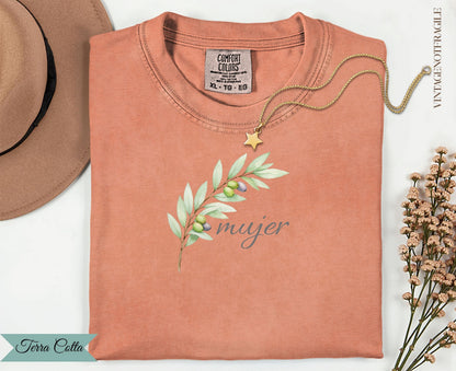 Coral t-shirt with "mujer" text and olive branch graphic, gold necklace.
