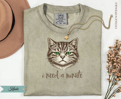 Khaki t-shirt with a cat illustration and "i need a minute" text.