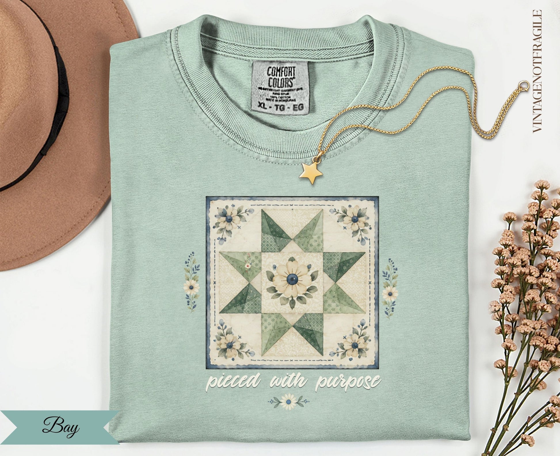 Light green t-shirt with a floral quilt block and "pieced with purpose" text.