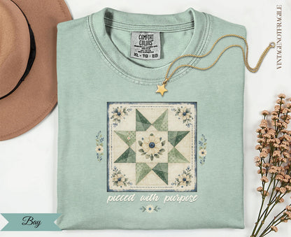 Light green t-shirt with a floral quilt block and "pieced with purpose" text.