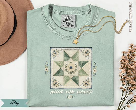 Light green t-shirt with a floral quilt block and "pieced with purpose" text.