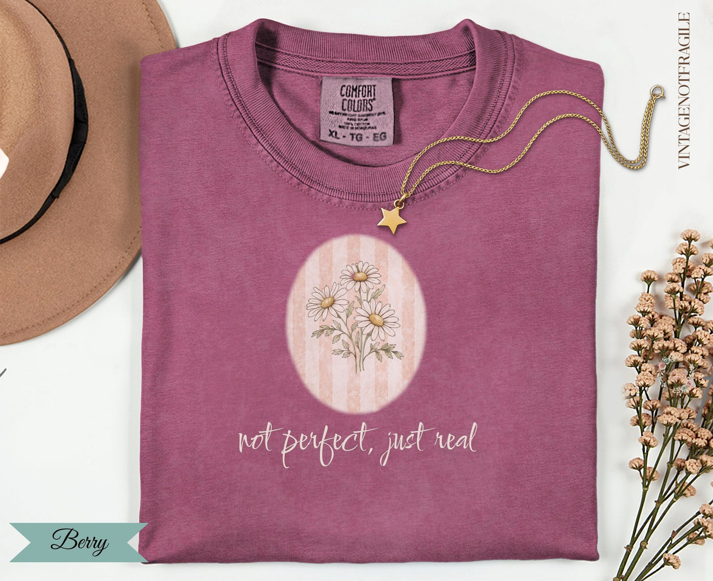 Mauve t-shirt with daisy graphic and "not perfect, just real" text.