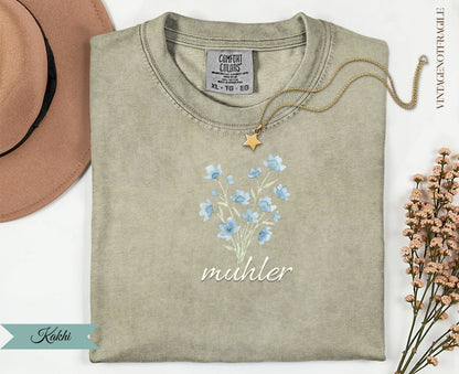 Comfort Colors khaki t-shirt with blue flowers and "muhler" text.