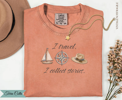 Orange t-shirt with "I travel. I collect stories." text and travel motifs.