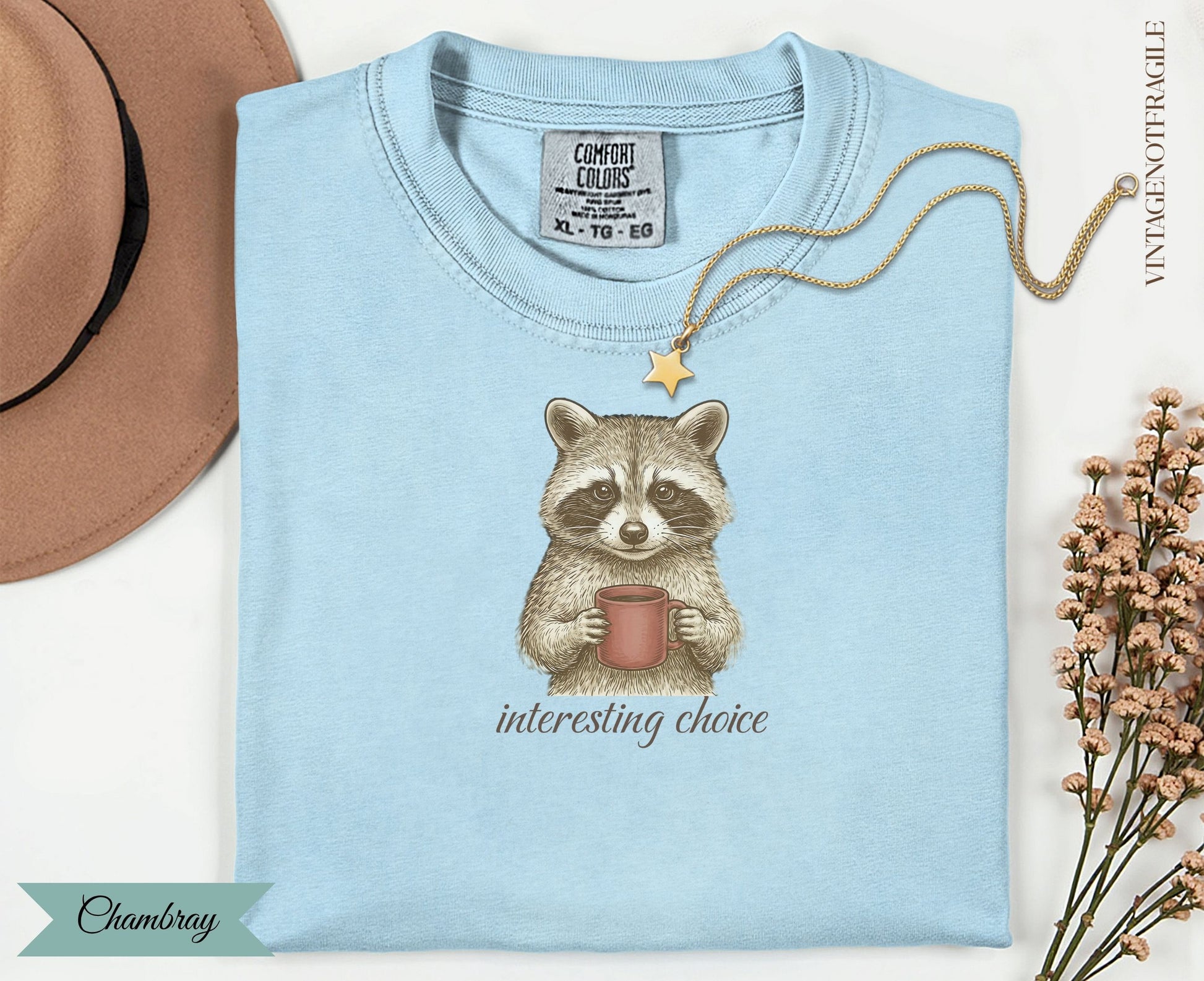 Light blue t-shirt with a raccoon holding coffee and the words "interesting choice".