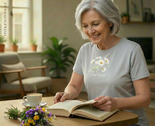 Gray t-shirt with embroidered daisies and "bean" text worn by a woman reading.