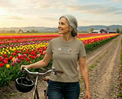 Woman in t-shirt with "I Travel I Collect Stories" text, holding bicycle in tulip field.